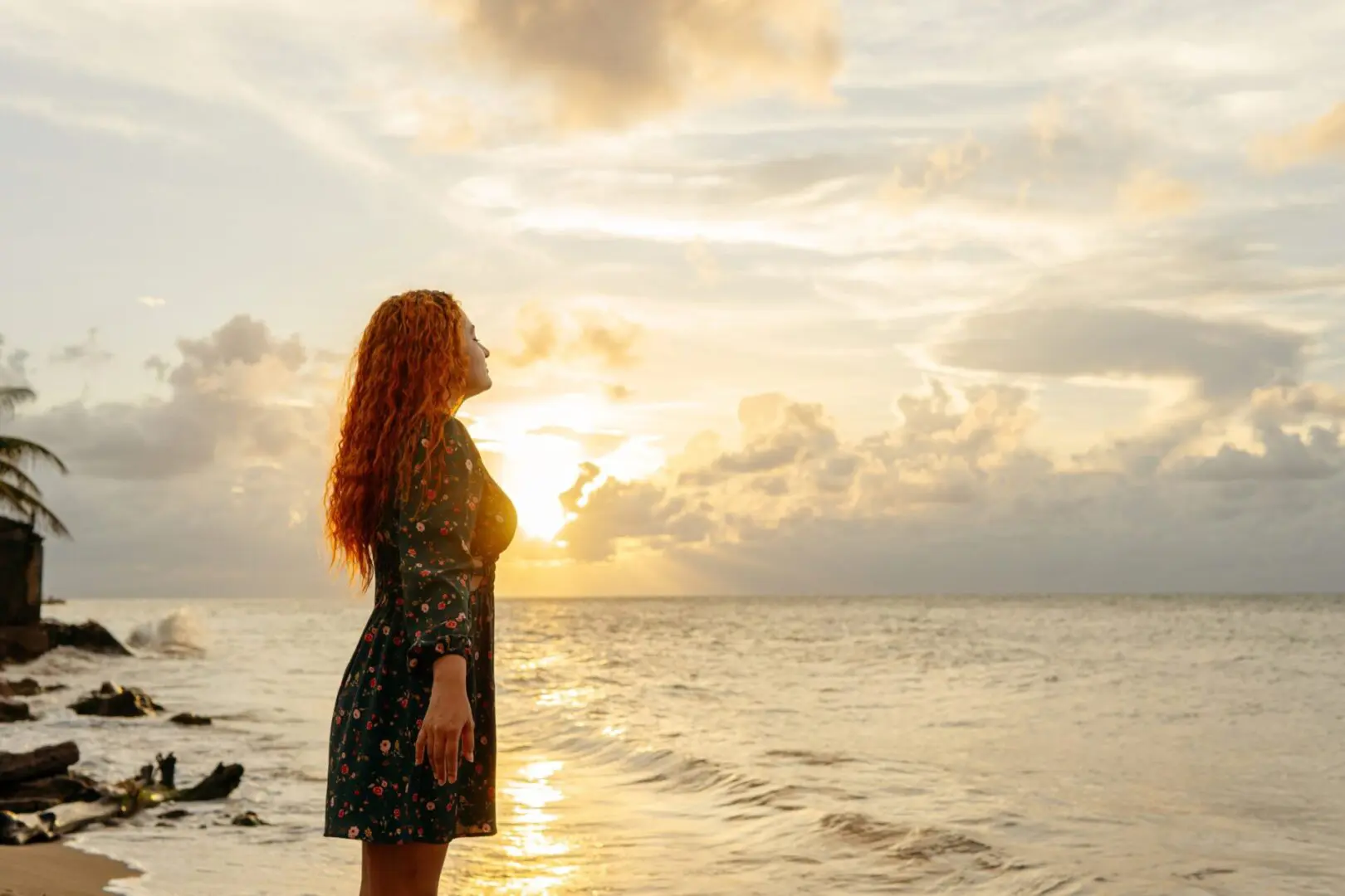 Woman standing by the ocean at sunset.