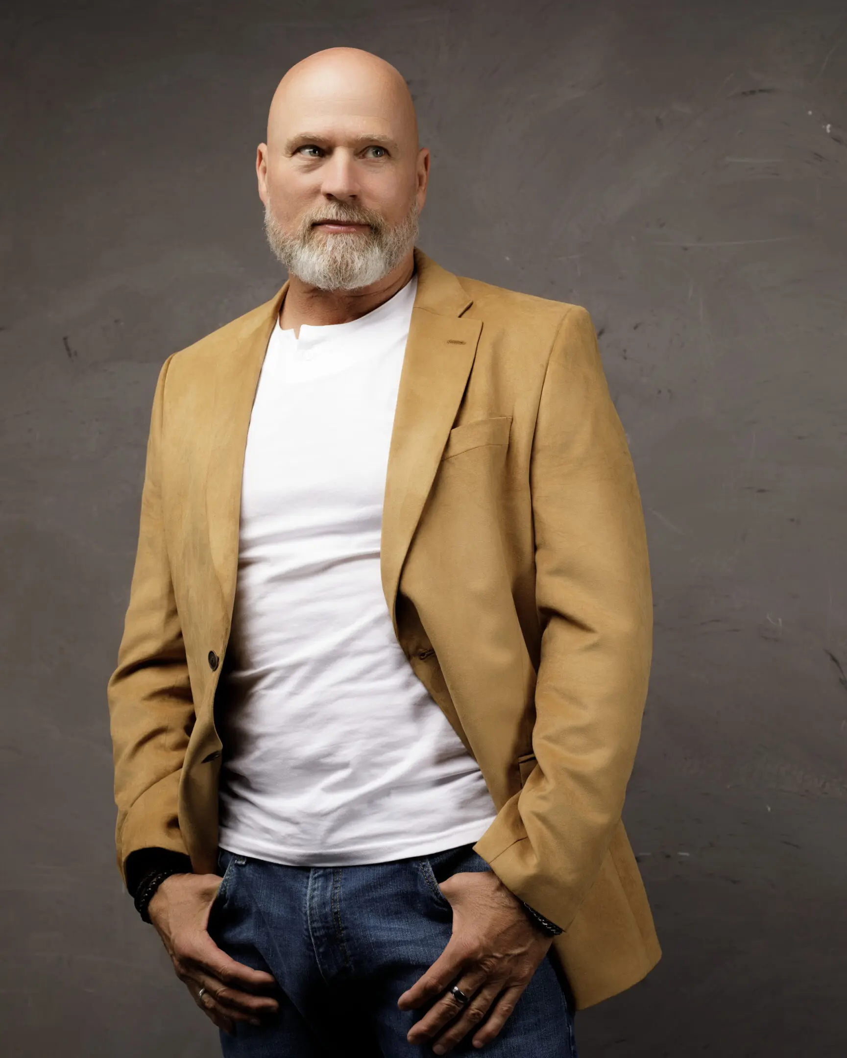 Mature man with beard wearing a mustard blazer and white shirt.